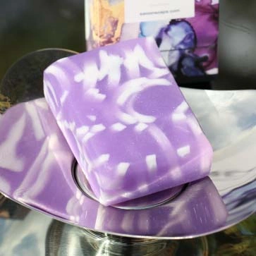 A translucent sparkling purple oblong bar of soap with white swirls. Minimum weight 95g.