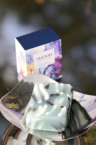 Translucent pale teal oblong soap with black and white ribbons through it. Minimum weight 95g.