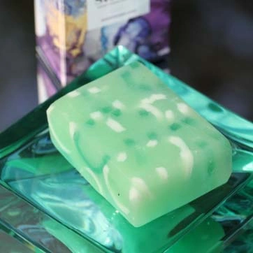 A sparkling translucent apple green oblong bar of soap with accents of stronger green and white.